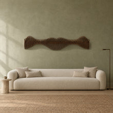 Anomaly II in walnut stain above a cream bouclé sofa in a sage plaster living room