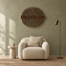 Orbit in walnut stain above a cream bouclé armchair in a sage plaster living room