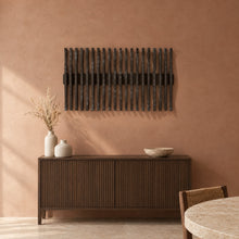 Resonance in black stain above a fluted dark-oak sideboard in a terracotta plaster dining room